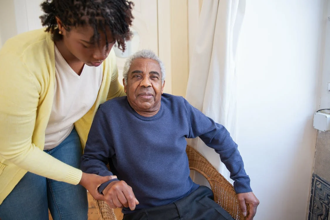 woman helping an elderly man sit
